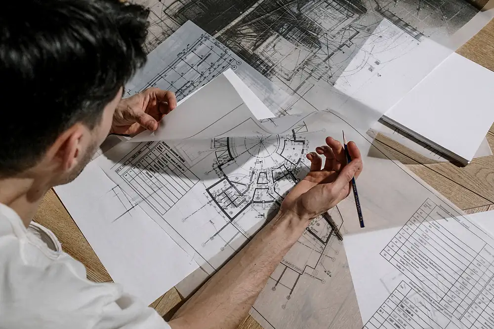 Arquiteto debruçado sobre pranchas de desenho impressas