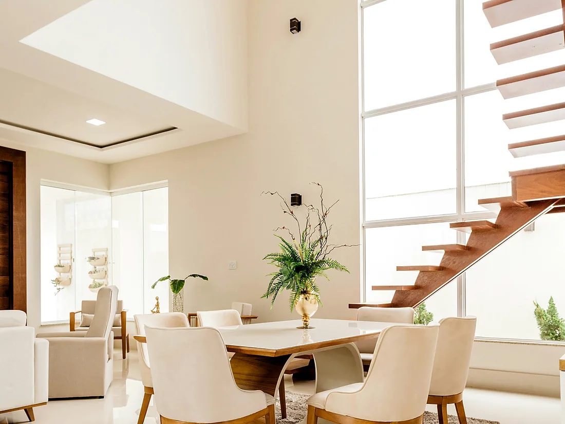 Sala do Apartamento CV depois da reforma, com pé-direito duplo, escada ao fundo e mesa junto à janela