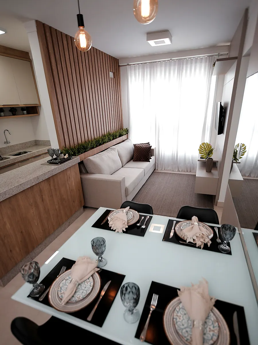 Sala de apartamento compacto com sofá claro encostado na bancada da cozinha